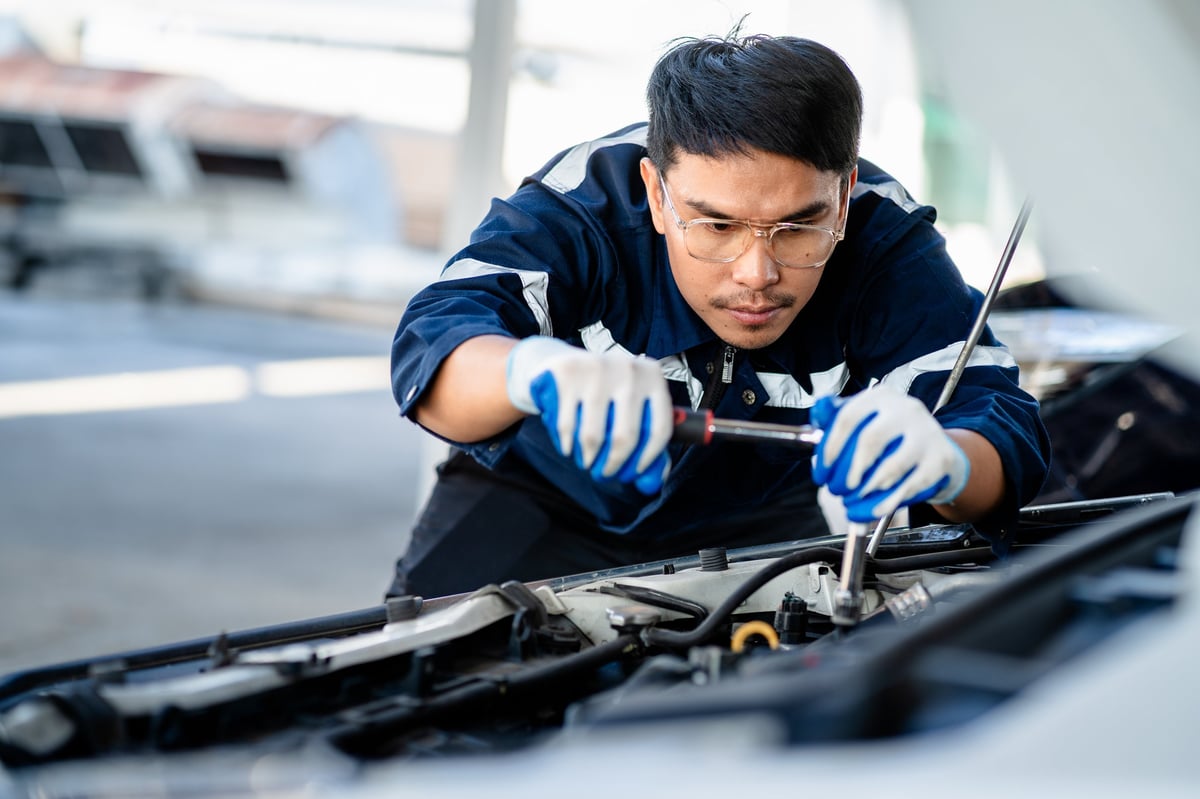 Auto mechanic repairman using a socket wrench working engine repair in the garage, changing spare parts, checking the mileage of the car, maintaining service automobile car