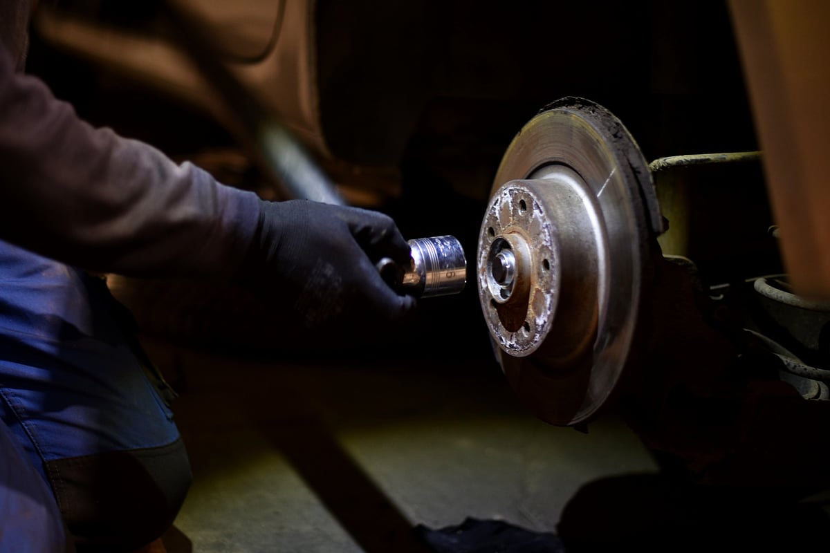 Mechanic man repairing brake disc brakes wheel