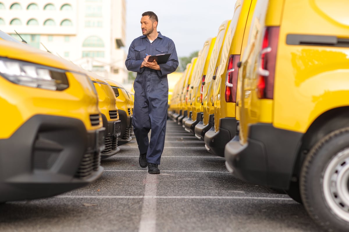 Mechanic inspecting a fleet of yellow vans